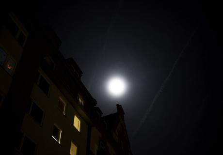 Zu sehen ist eine Straße bei Nacht mit einem hellen Mond